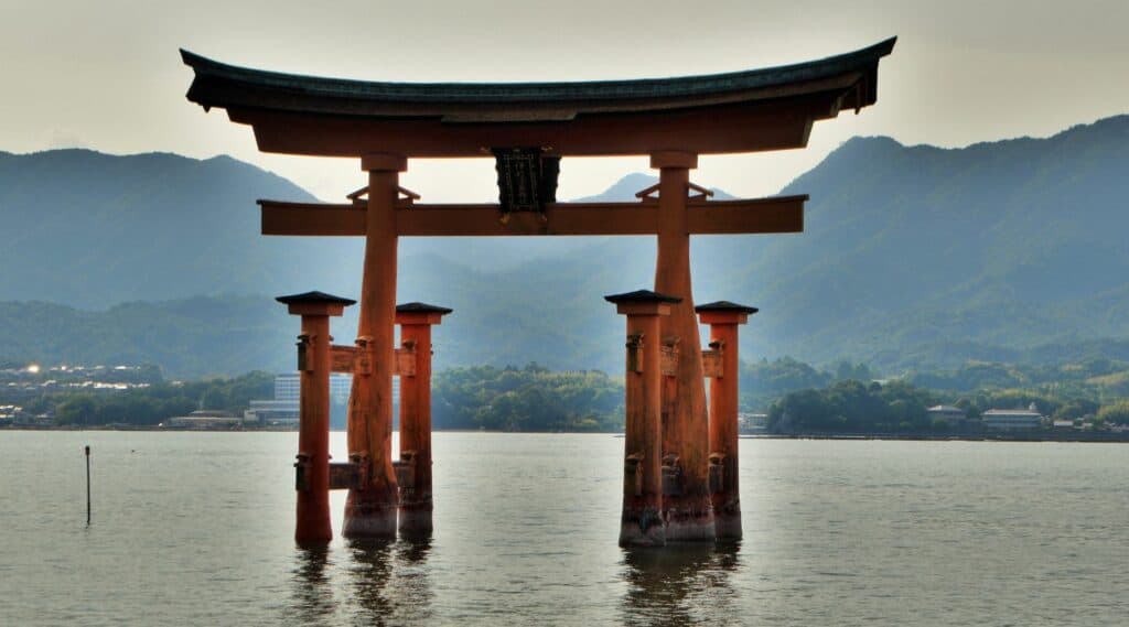 An orange shrine surrounded by water at dusk