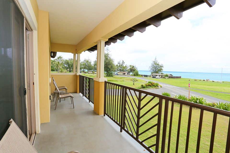 The porch of a yellow building with views of the ocean in the distance