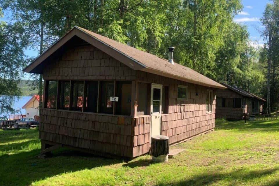 A cabin with wooden shingles next to a lake