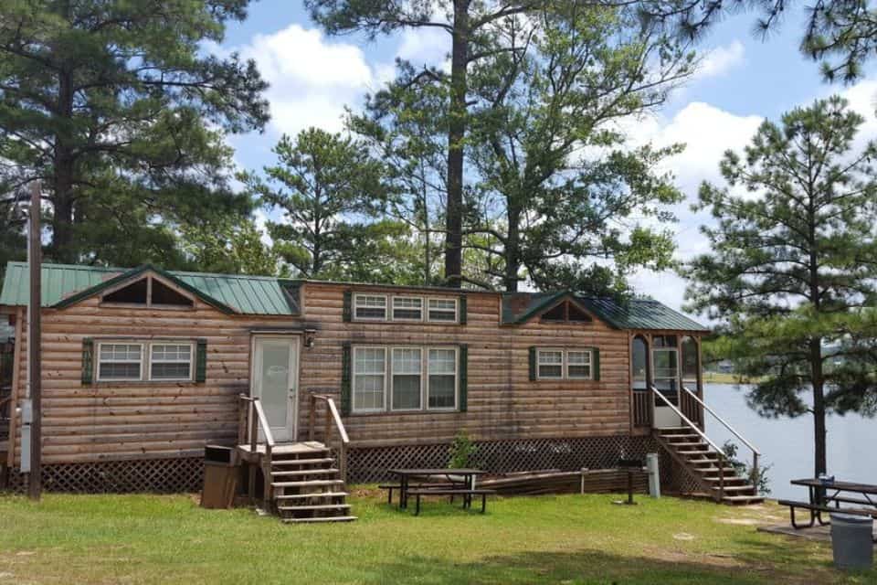 A large wooden duplex cabin next to a lake