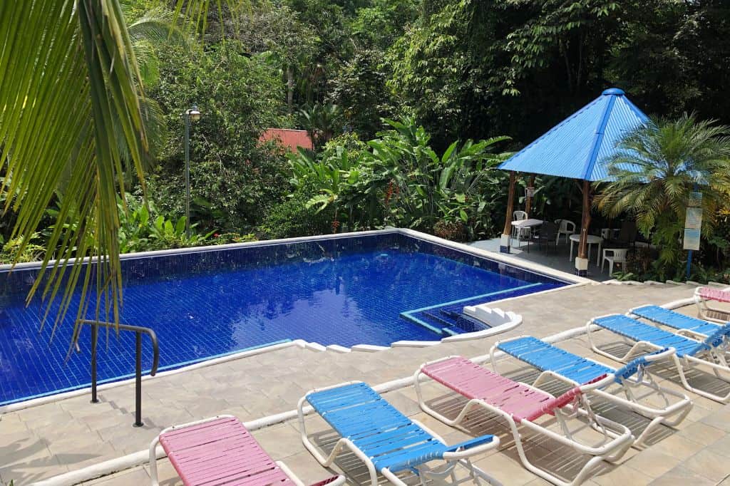 A pool surrounded by lounge chairs and lush jungle