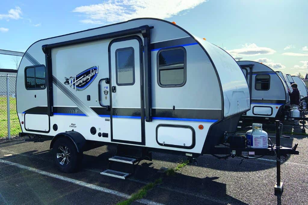 A row of small towable camping trailers in a parking lot