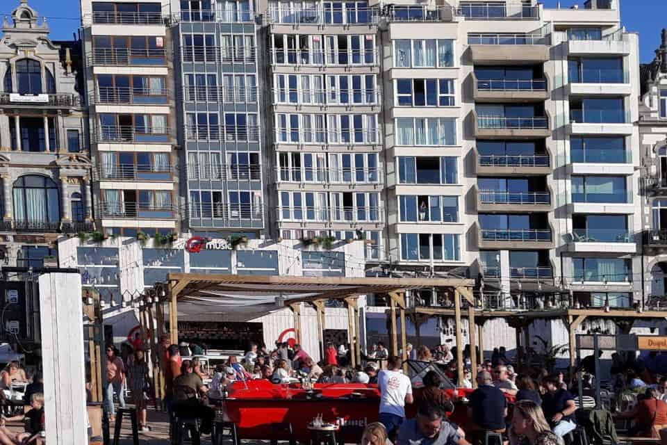 a crowded outdoor bar with apartment buildings behind it