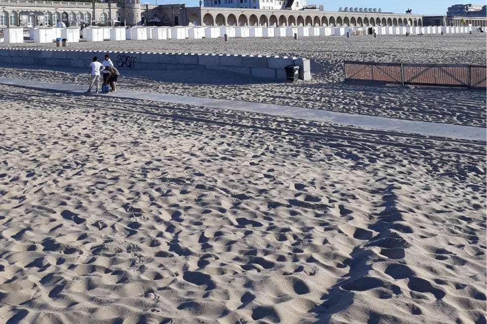 A wide beach with arched buildings in the background