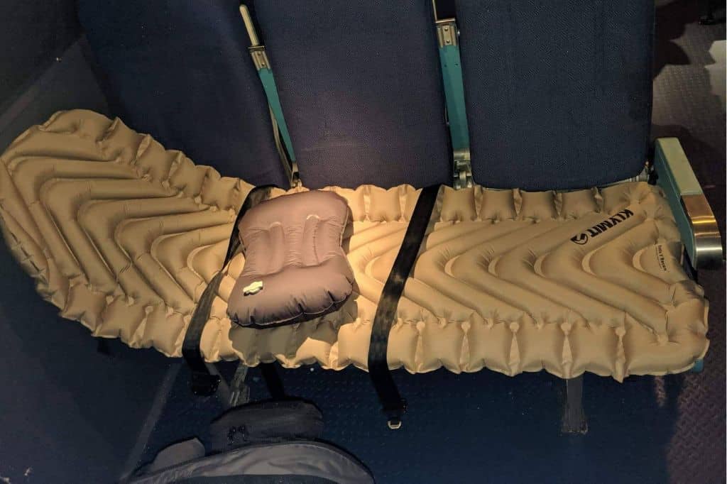 A beige inflatable mat on top of a row of airplane seats