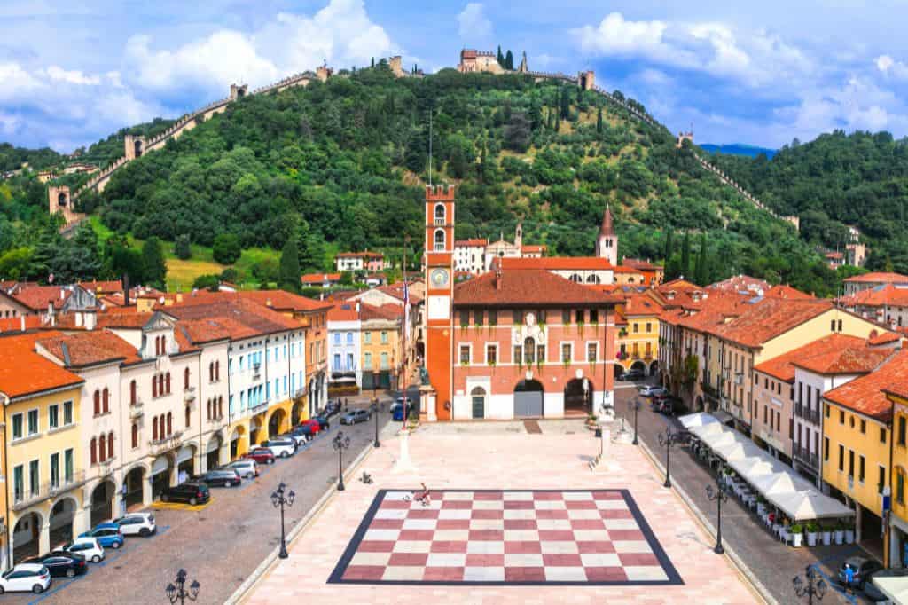 a town square surrounded by colorful buildings and a large chess board painted in the center