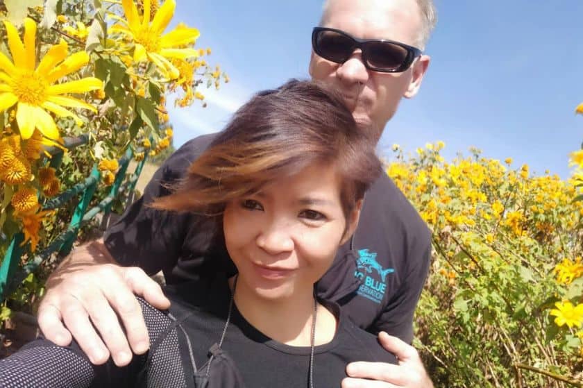 A man standing behind a woman in a field of flowers