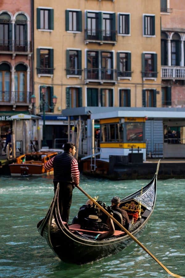 a gondolier guides visitors through the canals of venice