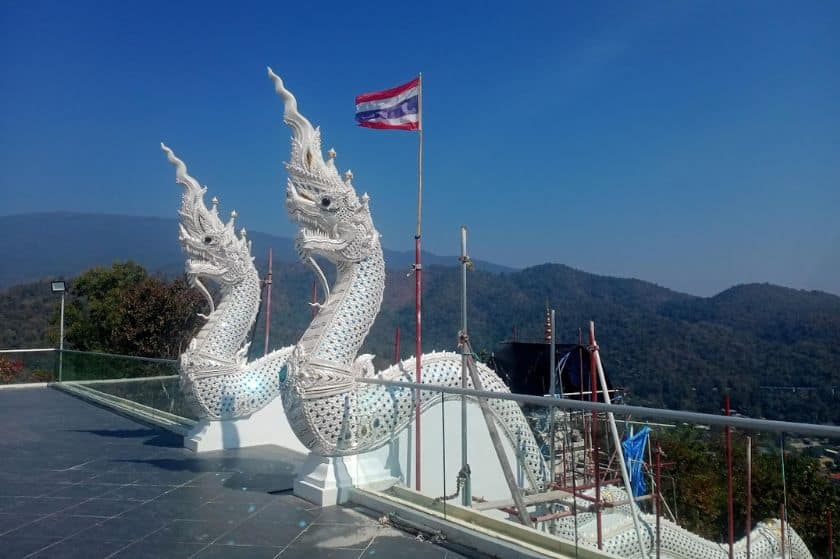 Two white dragon statues with mountains in the background.