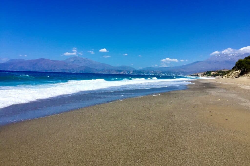 A stretch of sandy beach with mountain in the background