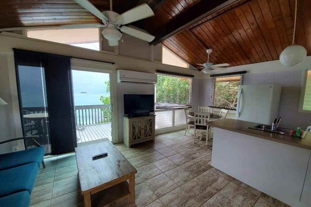 An open kitchen with living room leading out to a wooden overlooking the ocean