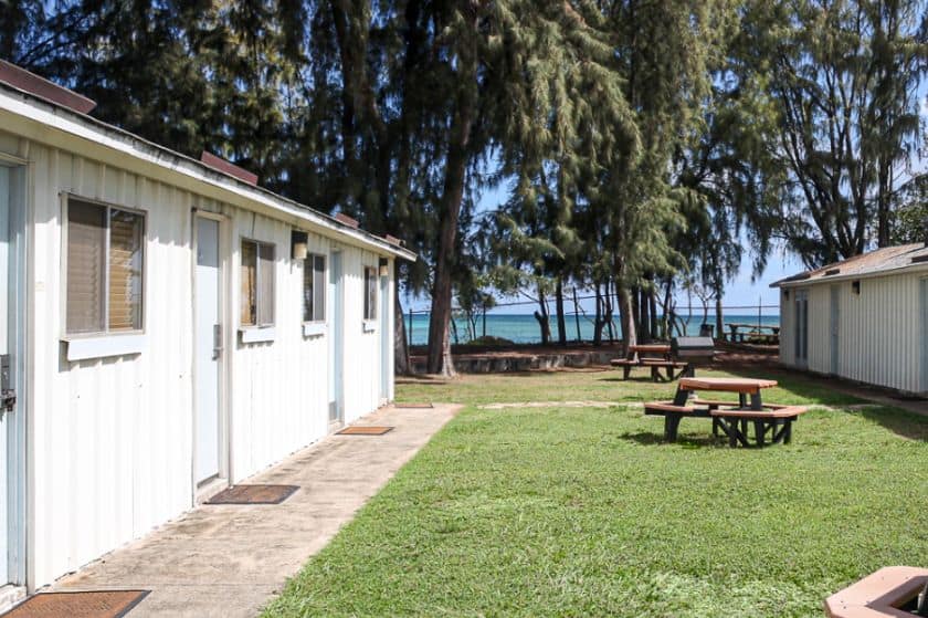 A simple motel-style building with a picnic table in front and the ocean in the background