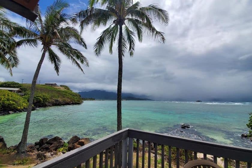 Ocean, mountains and palm trees viewed from a wooden balcony 