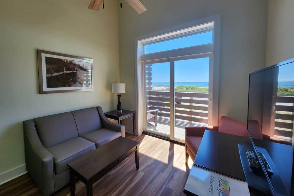 A living room with a sliding glass door leading to a balcony with ocean views