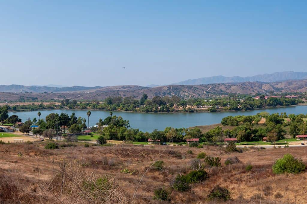 A small lake surrounded by trees and a few buildings