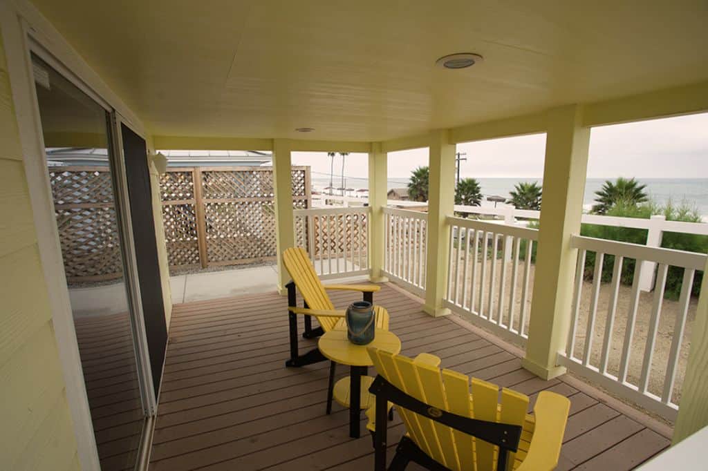 Yellow wooden chairs on a porch overlooking the beach