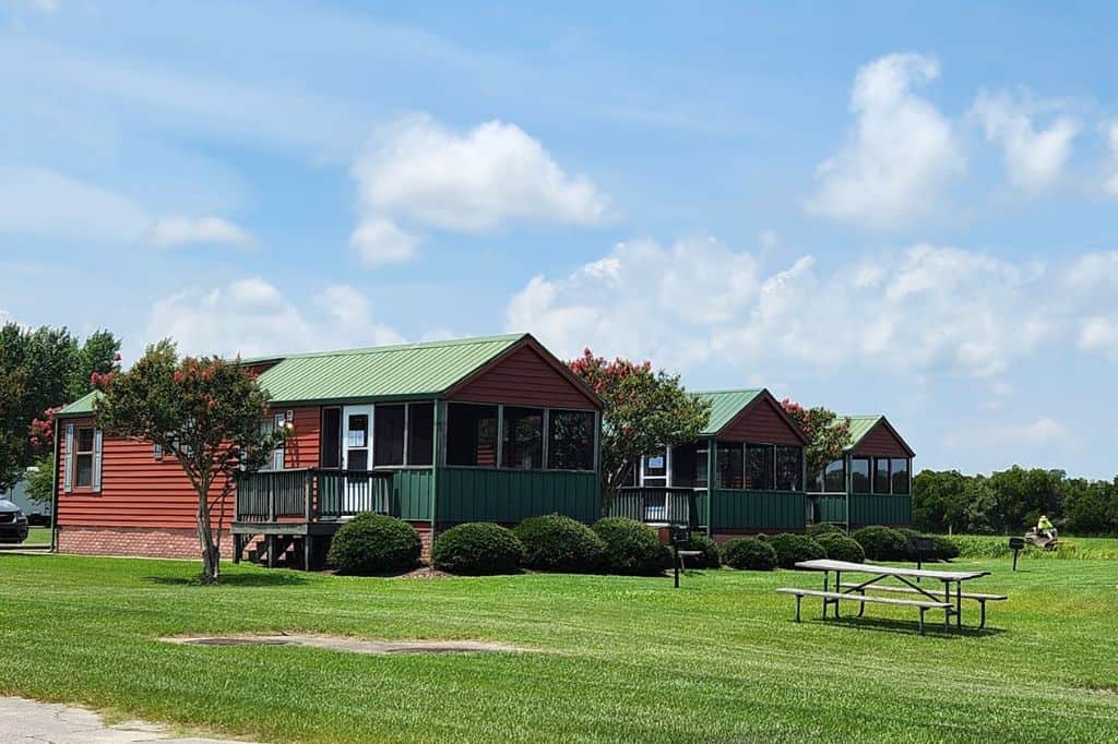 Rustic red and green cabins with porches on a grassy area